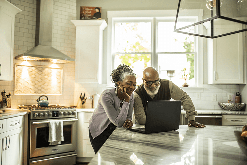 Woman and man looking at a laptop together on a kitchen counter
